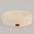 Load image into Gallery viewer, The Cocoon round dog and cat bed in cream bouclé, front view with the leather BONE & BOWS label