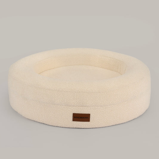 The Cocoon round dog and cat bed in cream bouclé, front view with the leather BONE & BOWS label