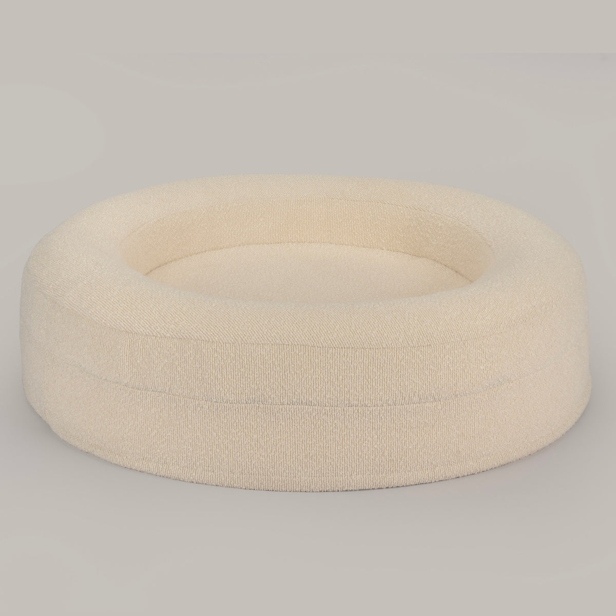The Cocoon in cream bouclé from a high angle, showing the raised bolster walls