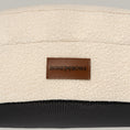 Load image into Gallery viewer, Close-up of the cream bouclé cover and leather BONE & BOWS label on The Cocoon

