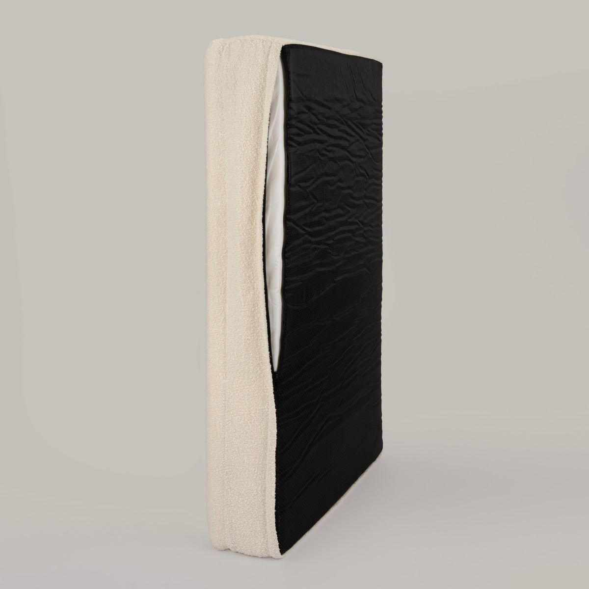 The Lounger on its side with the bouclé cover partly unzipped to show the inner liner